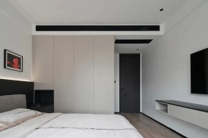 床侧打造一组通顶高柜，无把手面板设计让空间更具整体统一性，衣柜分割主体睡眠空间和步入式衣帽间，融为一