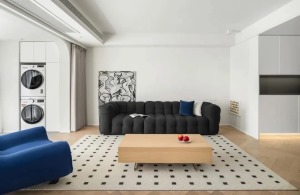 原木色人字铺地板+几何元素地毯，搭配顶面无主灯设计，视觉上具有空间延伸感，打通阳台纳入客厅面积，打造