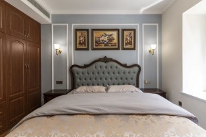 床头背景墙以雾霾蓝的乳胶漆填充，安静柔和。并以白色石膏线勾勒出些许造型，中间三幅油画与客厅呼应，营造