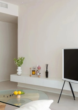 电视背景墙没有做造型，奶油色饰面搭配白色悬空电视柜，台面可作为摆置装饰，可移动电视支架让客厅更加灵活