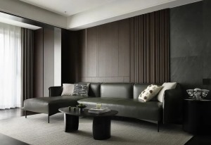 深橄榄绿皮质沙发，黑色的异形茶几，简约时尚又特别高级。沙发背景墙采用木饰面拼接岩板，规整而简洁的立面