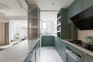 厨房，以豆蔻绿橱柜奠定色彩基调，纳入小阳台扩大使用面积，增设开放层板取代传统吊柜