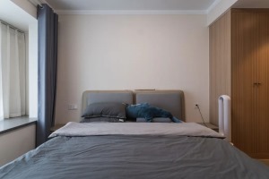灰蓝色软包床头+同色系床品，搭配简约留白的背景墙，搭建一方悠闲惬意的居所。原木色衣柜，一门到顶，充分