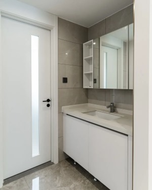 卫生间干区外移，以白色房门为分割实现干湿分离，整体铺贴大理石瓷砖，白色浴室柜与镜柜开放格，呼应整体空