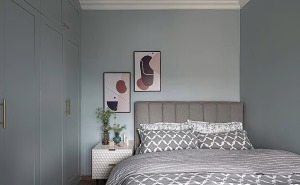 次卧灰色的床品搭配上浅绿色调的墙面与衣柜，再配上精美的装饰画、雪白的床头柜以及绿植的点缀