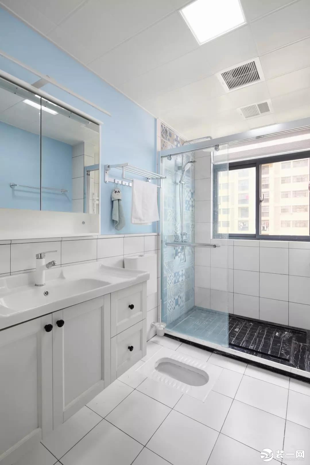 卫生间洗漱区的白色地砖延续到了腰线高处，配合天蓝色的墙面，营造格外清新的氛围。而淋浴间则以墙面花砖和