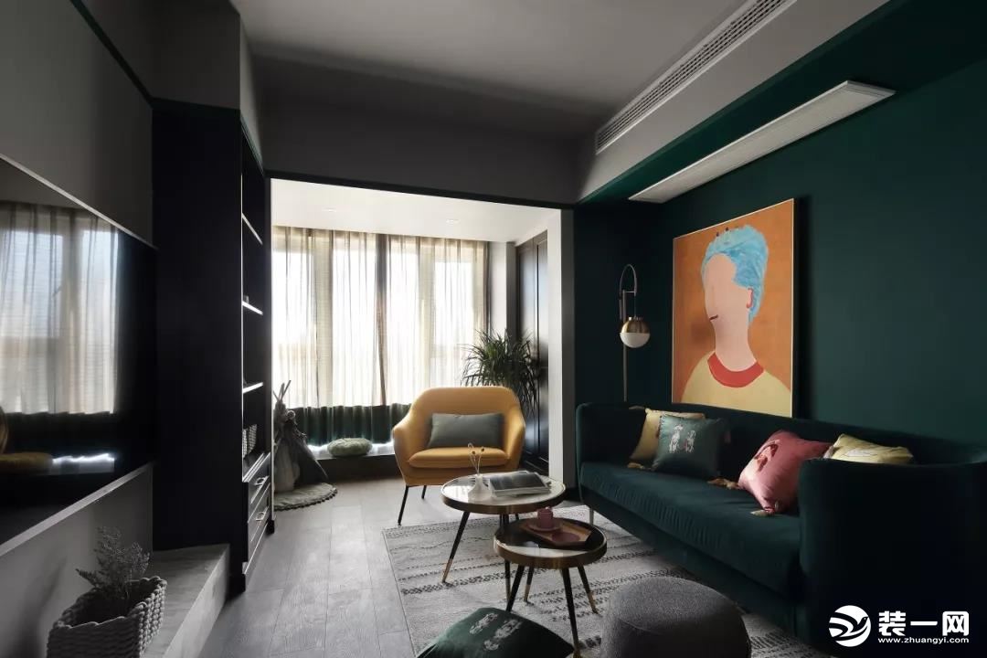 ▲墨绿色的沙发墙与布艺沙发，挂上一幅橙色的卡通人像装饰画，还有一张黄色的布艺沙发椅，带来一个安静端庄