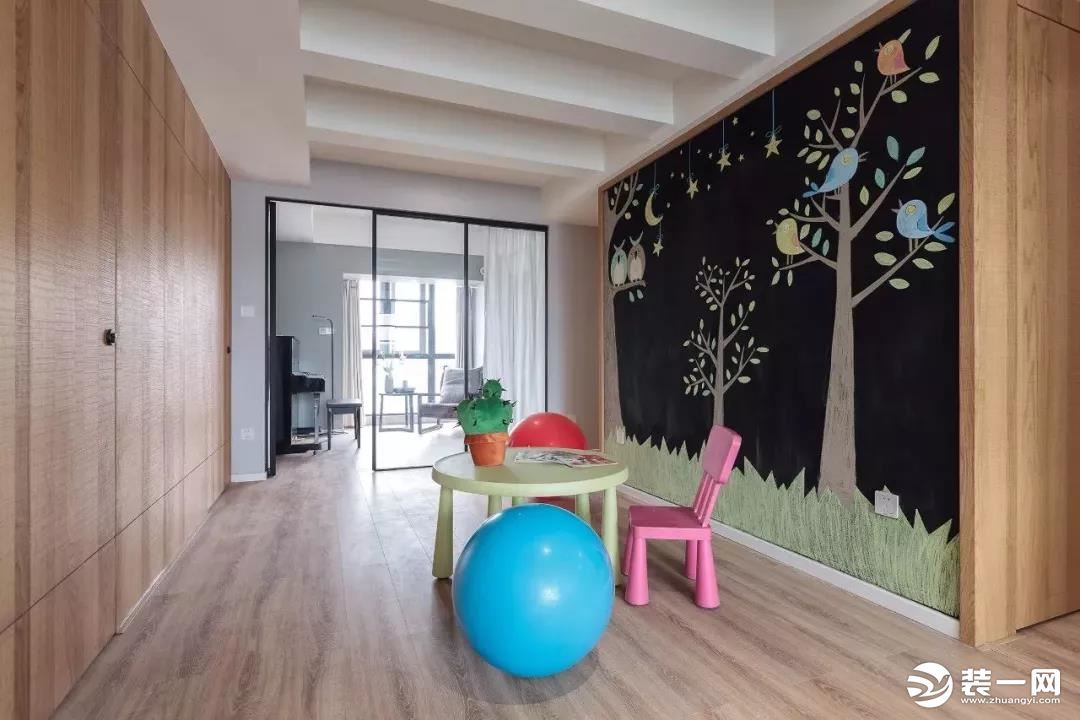木色清香的过道，容下了儿童桌椅，用作儿童玩区，黑色背景墙上的卡通彩绘，给简单的过道增添了一笔灵动的色