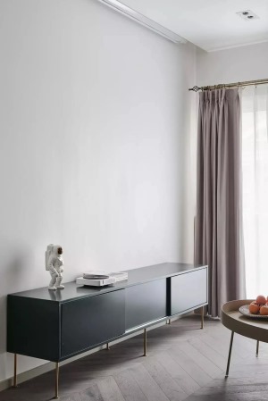  客厅布置采取简洁实用的风格，养眼舒适。莫兰迪粉的窗帘与灰绿色电视柜，搭配出了复古的美感，几处金色元