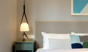 浅灰色的布艺床靠背，以白色为主调的舒适床品，加以穿插其间的蓝绿色调，在床头吊灯的氛围烘托下，简约时尚