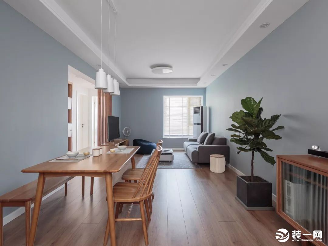整体空间以灰蓝色为主调，灰色布艺沙发简约而有质感，木质家具与清新绿植的加入，营造舒适惬意的生活氛围。