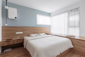 主卧定制的木质床体，与床头柜、床头护墙板以及飘窗组合成一体的设计，让空间利用得简洁而大气。