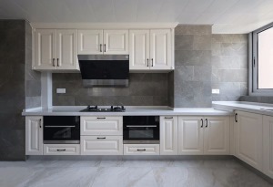  厨房空间较大，设计师合理利用空间满足屋主日常烹饪需求。橱柜依旧选用白色，更凸显出灰色墙砖的不俗质感