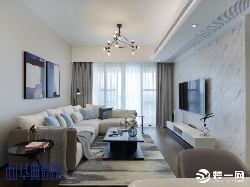 客厅是极简的现代风格：简单的几何形吊灯、干净留白的墙壁、温润木质的地板配上水墨画一样的地毯、点缀蓝色