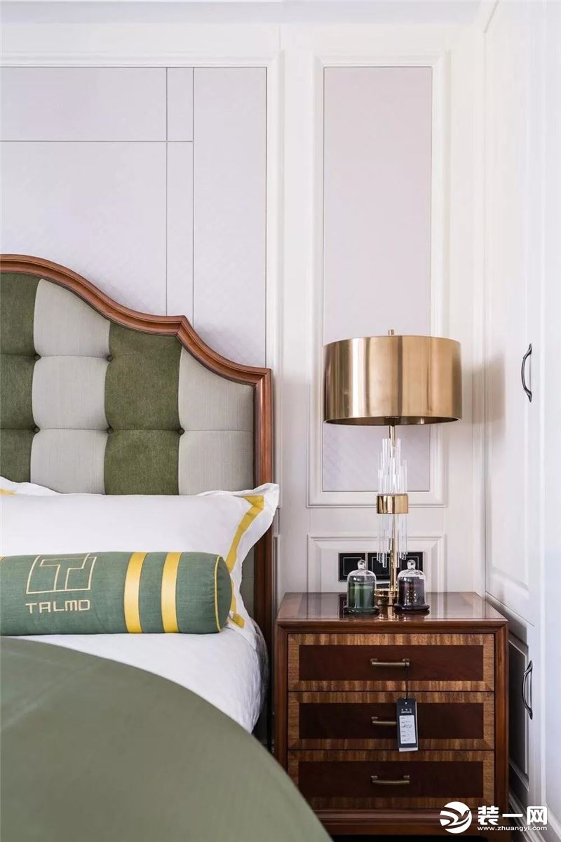 次卧灰绿相间的布艺床头靠垫，搭配交叠木色的床头柜，一盏精致的铜艺床头灯，显得清新中不失端庄。