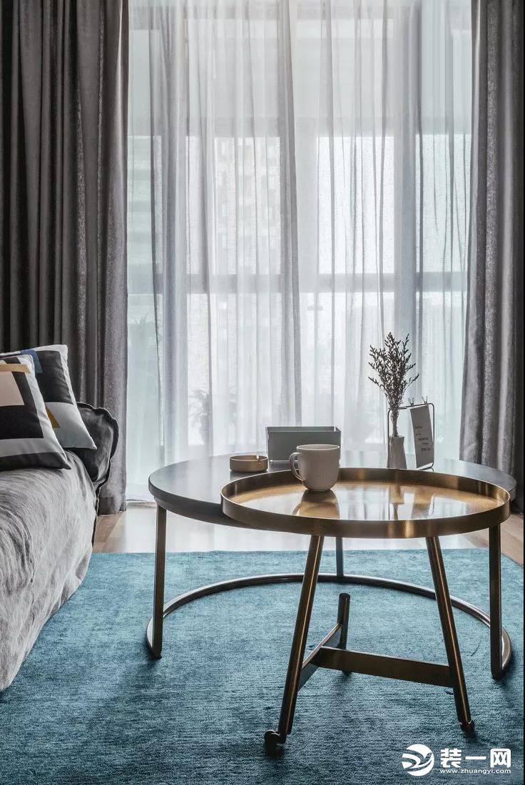 客厅的蓝色地毯与灰色布艺沙发、沙发墙的冷色调相互映衬，结合金属质感的茶几，显得。优雅轻奢