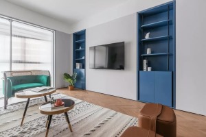 电视背景墙延续简约的风格设计，内嵌式蓝色储物柜特意设计成对称样式，达到平衡整个区域重心的目的。