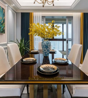 餐厅铜艺底座+黑色台面的餐桌，以台面的一道黄色勾勒出了活力感，结合精致的家具和一瓶鲜花，餐桌上是满载
