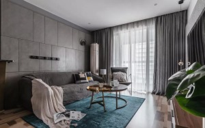 客厅的蓝色地毯与灰色布艺沙发、沙发墙的冷色调相互映衬，结合金属质感的茶几，显得优雅轻奢。