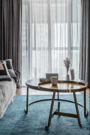 客厅的蓝色地毯与灰色布艺沙发、沙发墙的冷色调相互映衬，结合金属质感的茶几，显得。优雅轻奢