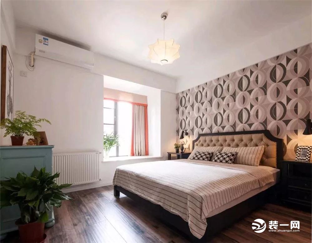 卧室床头贴着独特的圆形交叉的壁纸，同时有个舒适的小飘窗，床尾的蓝色斗柜，搭配上清新的绿植，整体空间都