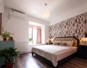 卧室床头贴着独特的圆形交叉的壁纸，同时有个舒适的小飘窗，床尾的蓝色斗柜，搭配上清新的绿植，整体空间都
