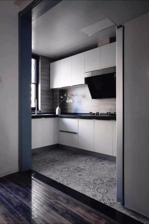 厨房以化妆作为地面，结合墙面整体灰色调的墙砖，搭配上白色橱柜与黑色电器，呈现出一个简约黑白灰的空间