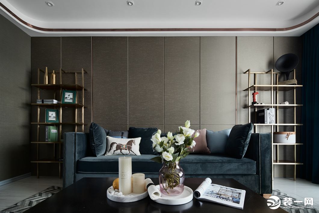 沙发墙以棕色的背景，搭配上两侧的金属收纳架，布置深蓝色布艺沙发，深色桃木的茶几桌面摆放的花束，整个空