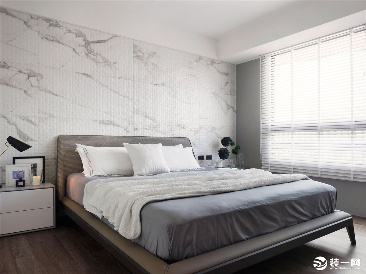 灰色布艺床布置白色床单，墙面大理石的设计整体简约朴素的空间风格，形成了和谐舒适的呼应