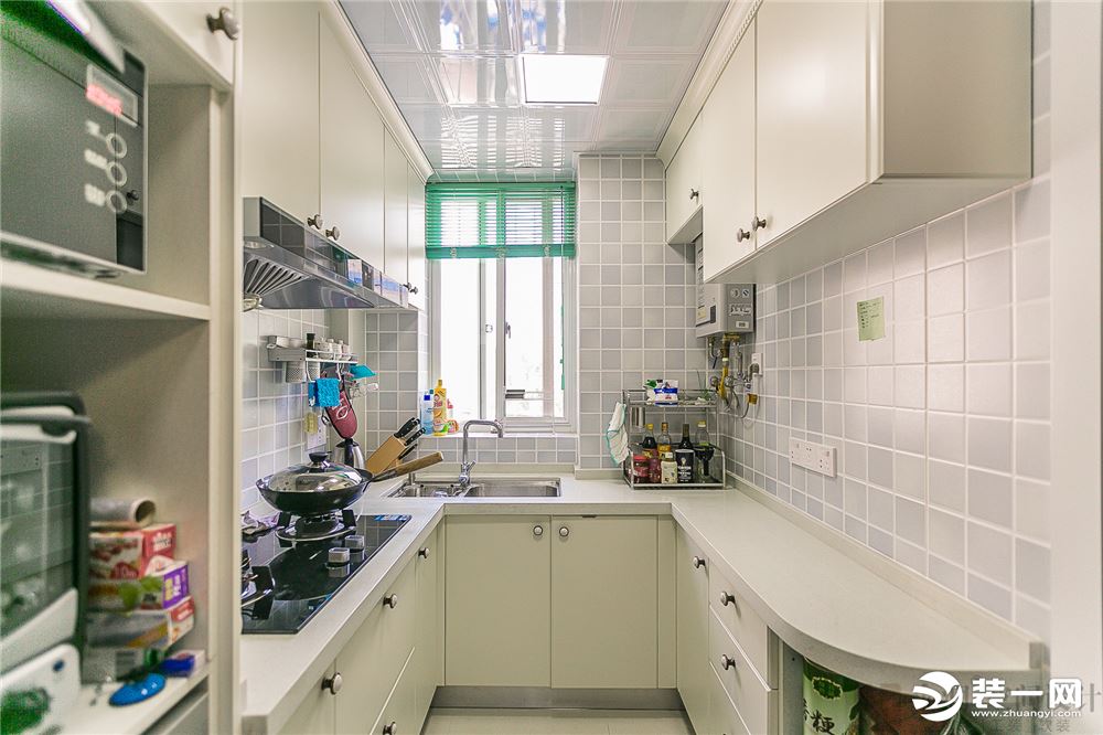 厨房浅蓝色的小方块墙砖和白色的橱柜形成鲜明的对比，旁边的设备柜高柜设计，让厨房有了更高的利用率