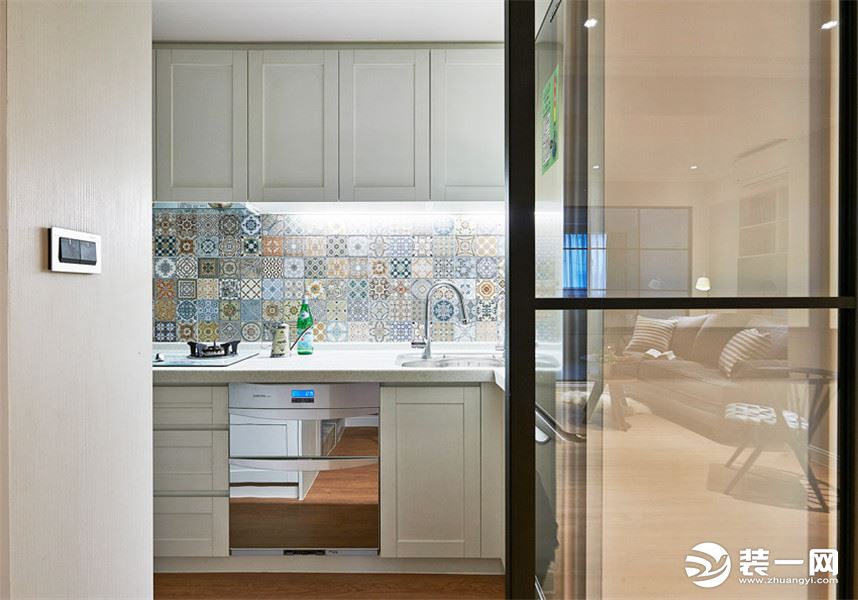 位于玄关旁的厨房设有玻璃拉门以隔绝油烟，简单 L 字型流理台搭配收纳功能完整的纯白系统柜.