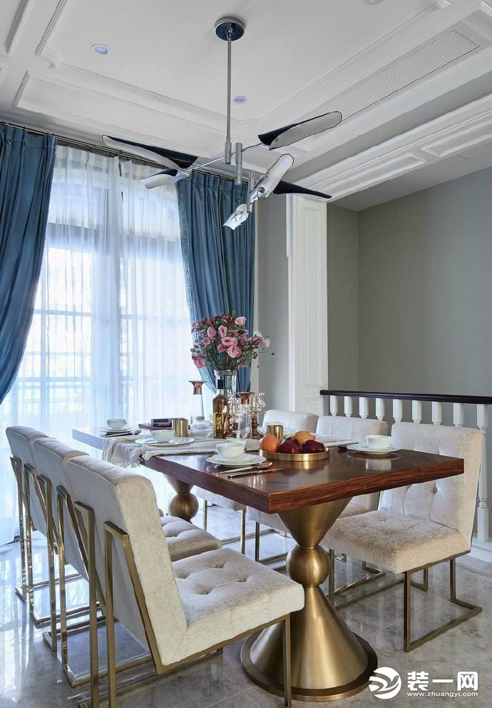 顶上细腻的雕花内嵌金箔，光的演绎营造，将贵气蔓延室内，拼接的墙面颇具立体感视觉效果，天蓝色的窗帘与餐
