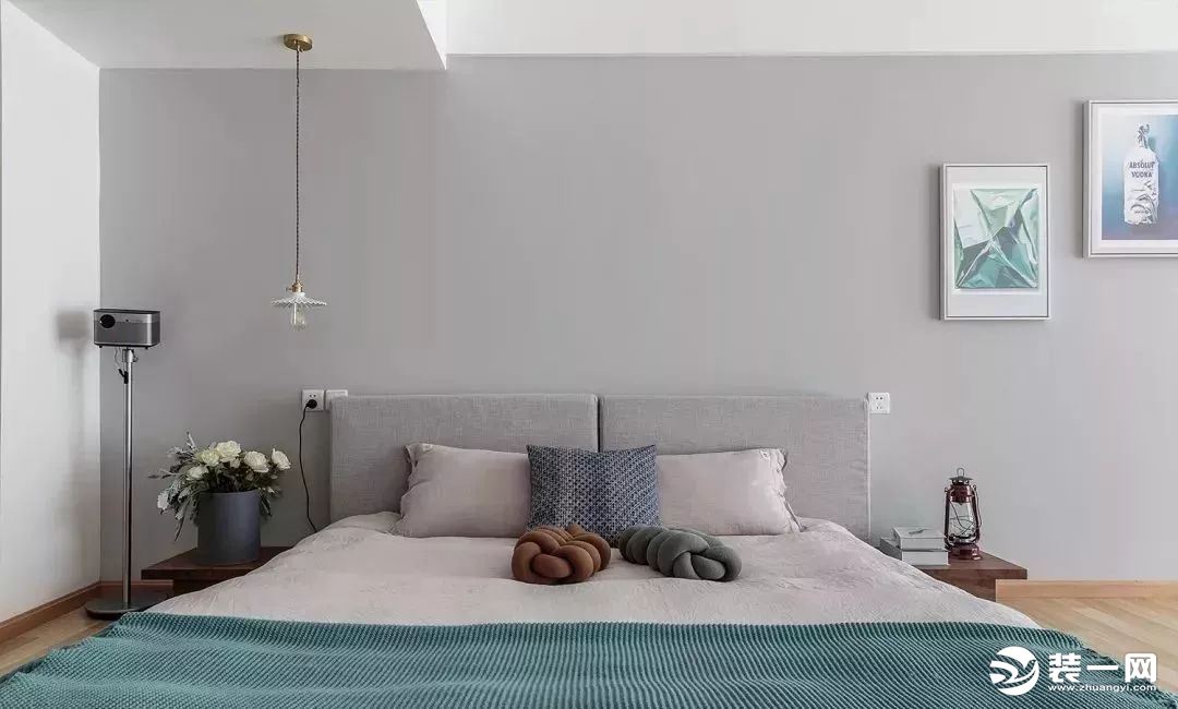 床头背景墙刷成浅灰色的，垂下来一盏吊灯照明，床头两侧还有小巧的床头柜，床铺也是素雅的颜色，很舒服，