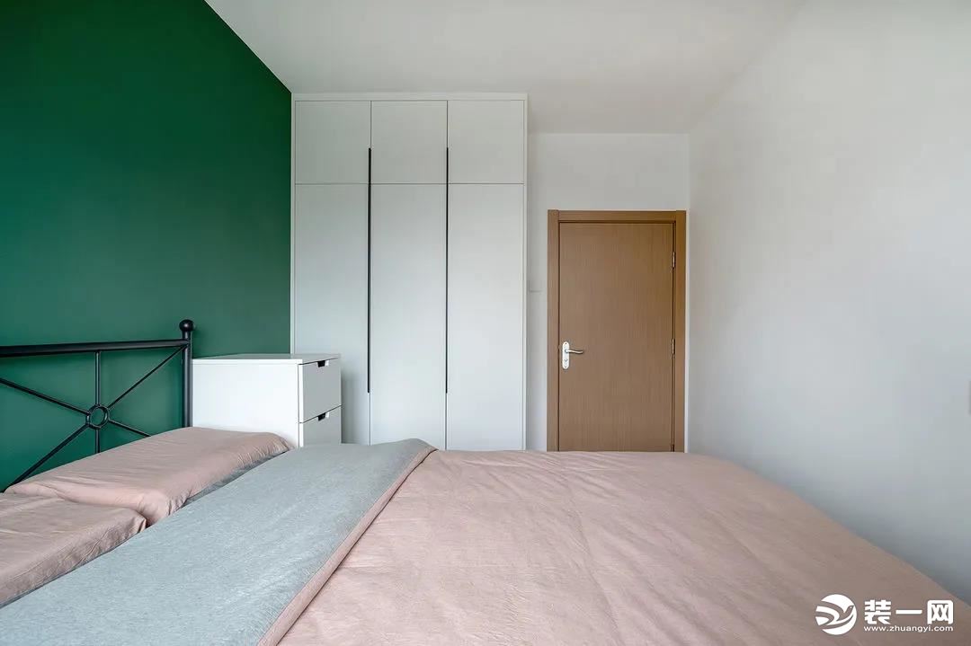 卧室非常简约，背景墙与常见的设计有所不同，采用分色处理。粉色和绿色比例为3：1，墙面粉色又与床品相