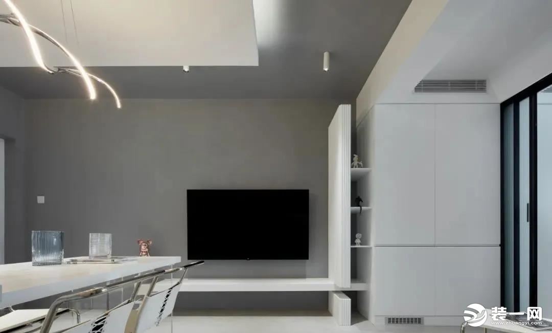 ▲ 电视背景贯穿客餐厅，纯粹的灰色墙面搭配白色柜体，家具颜色在选择上也保持统一，显得空间尤为整洁