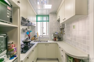 廚房淺藍色的小方塊墻磚和白色的櫥柜形成鮮明的對比，旁邊的設備柜高柜設計，讓廚房有了更高的利用率