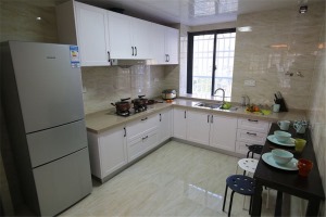 厨房延用了客餐厅的基调，雅色的大理石瓷砖搭配白色一体式的橱柜设计，提升了整个空间的洁净度。