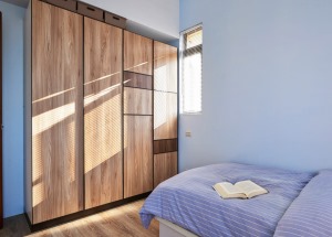 原木木纹的衣柜，最大限度的保留了最自然的气息。蓝白条纹的床品，温馨舒适。