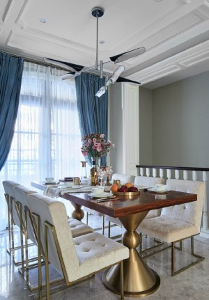 顶上细腻的雕花内嵌金箔，光的演绎营造，将贵气蔓延室内，拼接的墙面颇具立体感视觉效果，天蓝色的窗帘与餐