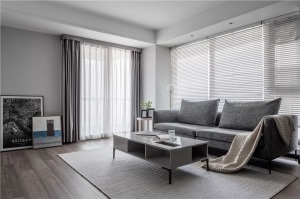 沙发墙挨着窗户白色，百叶帘的窗户，光影斑驳的光线与视觉效果，让空间显得充满简约舒适的气质。