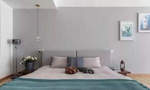 床头背景墙刷成浅灰色的，垂下来一盏吊灯照明，床头两侧还有小巧的床头柜，床铺也是素雅的颜色，很舒服，