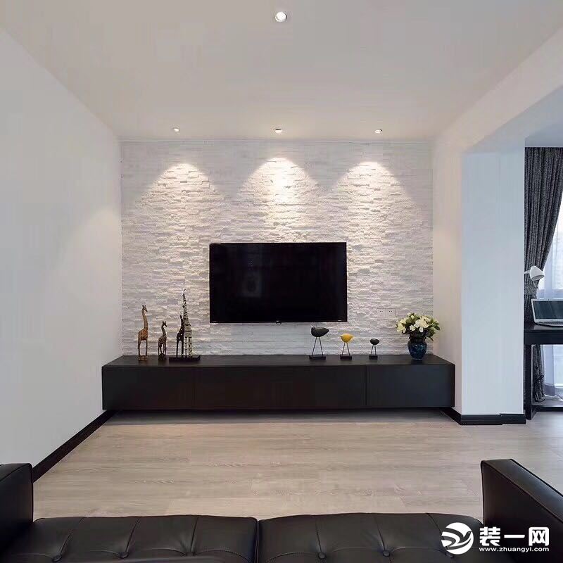沙发对面是定制的电视柜，白色文化砖在三盏射灯的弧形光线下肌理分明，成为不落俗的装饰。