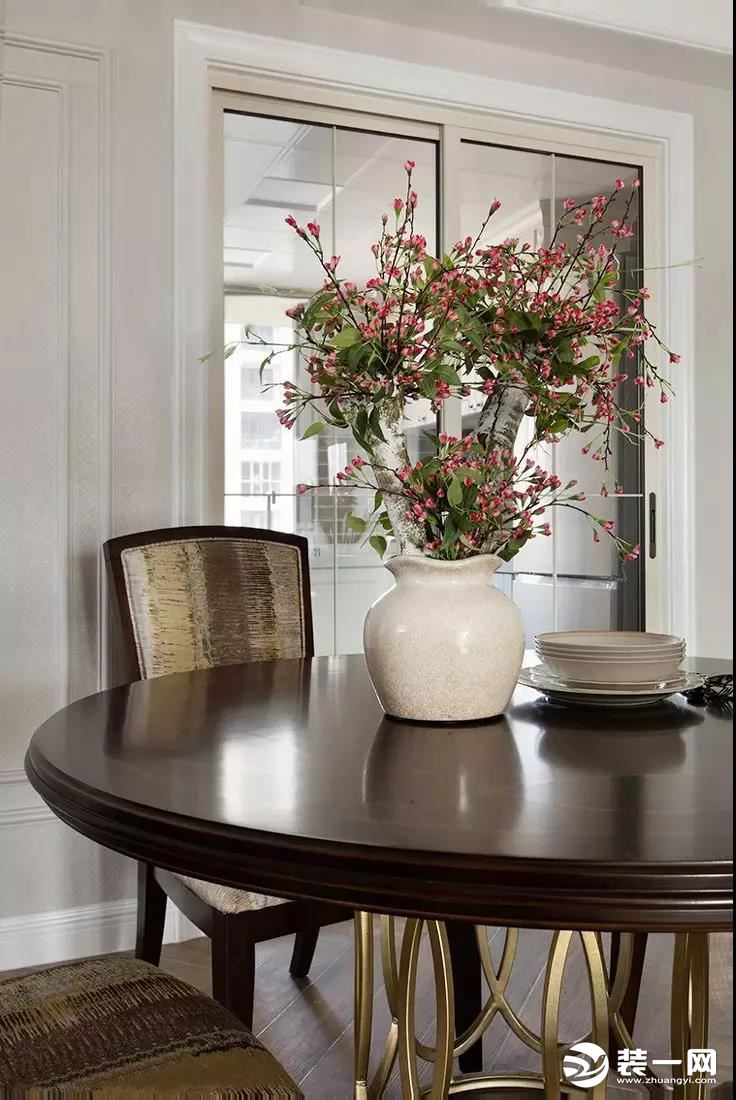  华美不失沉稳的餐椅配以明媚的花束增添清新雅致的味道，玻璃推拉门的设计使餐厅与厨房空间都明亮通透。