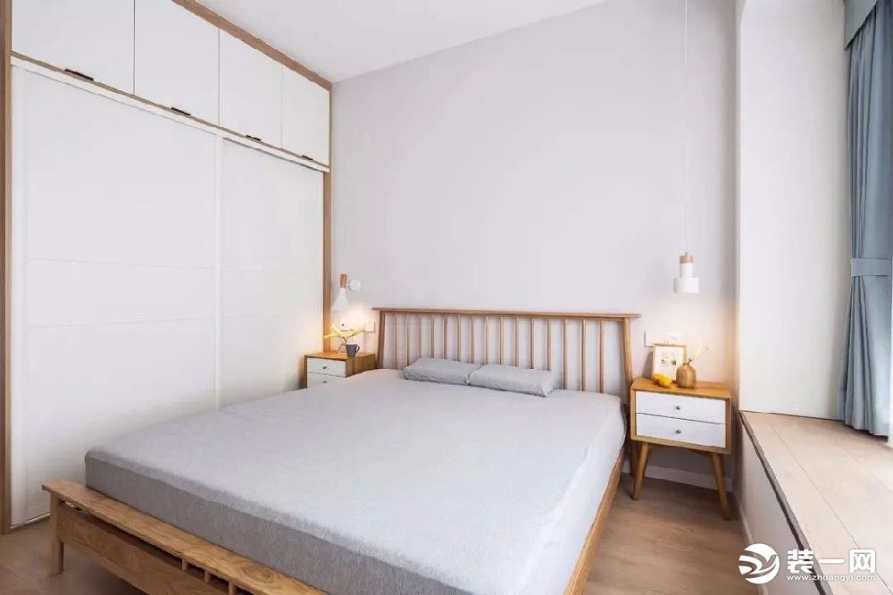 主卧室以白色和木色为主，搭配浅灰色的床品，营造出自然休闲的居住氛围。床两侧分别是大衣柜和飘窗榻榻米，