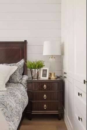  深色的实木床与床头柜结合美式的细节软装，整个卧室都沉浸在端庄柔和的气息中。