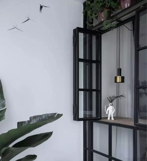 ▲ 阳台摆放一把伊姆斯椅，高低错落的绿植富有生机，结合复古的极窄黑框窗户，共同打造自然清新而又惬意的