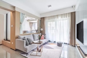 浅灰色布艺沙发简洁舒适，灰色几何图案的地毯增强空间层次，粉色的抱枕及绿植点缀让空间变得更加活跃。