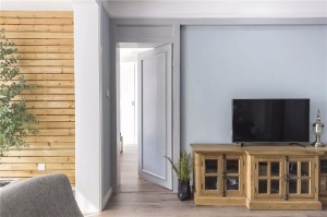 电视墙左侧还有一扇隐形门，与电视墙边框造型结合一体非常和谐，木质电视柜沉稳而有质感，充满了复古格调。