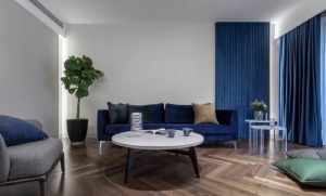 客厅静雅的深蓝色沙发、精致的法兰绒硬包，在造型语言上比例适当，横竖交错生辉。窗帘色彩与背 景的硬包及