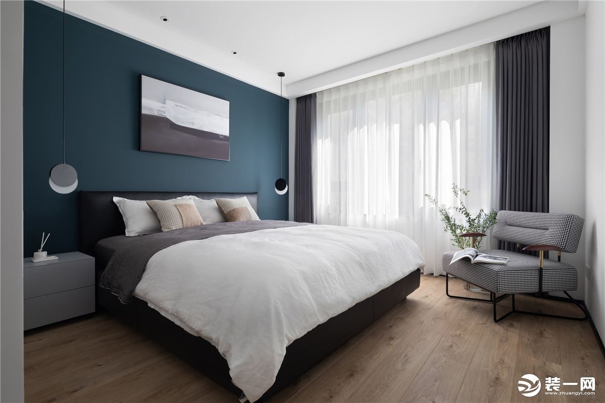 床头使用深蓝色的墙面，黑色皮质床质感十足，搭配灰色布艺单椅，素雅而又一丝活泼，岁月静好，悠然的生活气